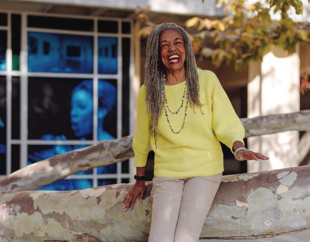 Mary Watson-Bruce, Ph.D. ’82 sitting on a tree branch and smiling