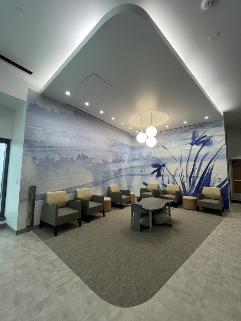A waiting area inside a hospital building features California coastal landscapes
