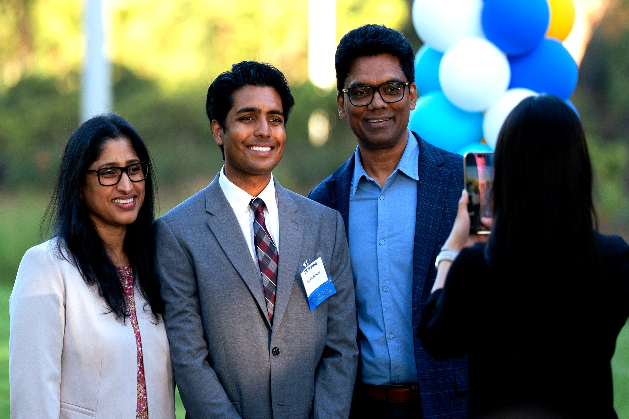 Three people smiling and posing together for a photo at a lively event.