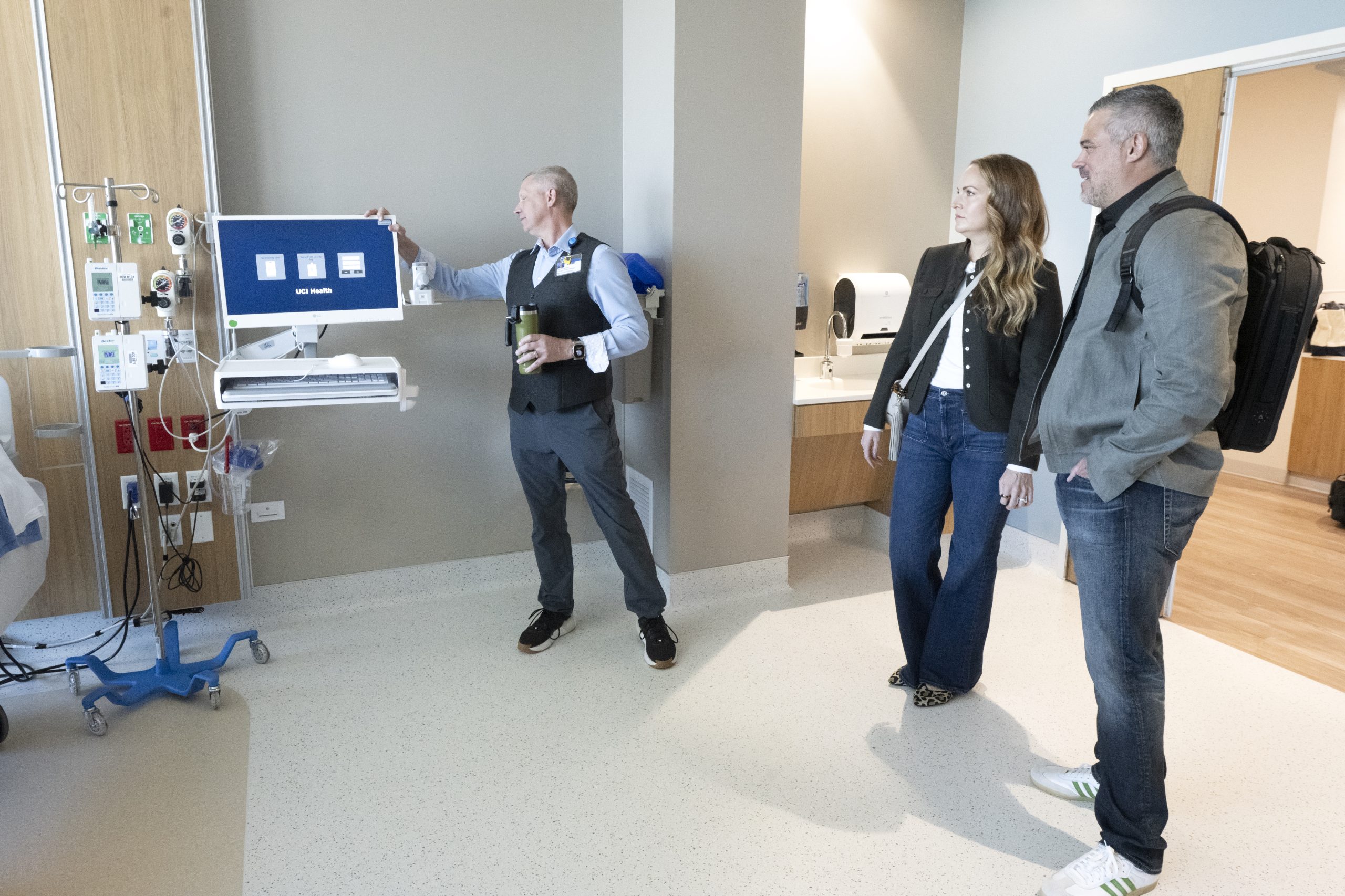 A couple watches a hospital worker turn on a computer in a hospital room