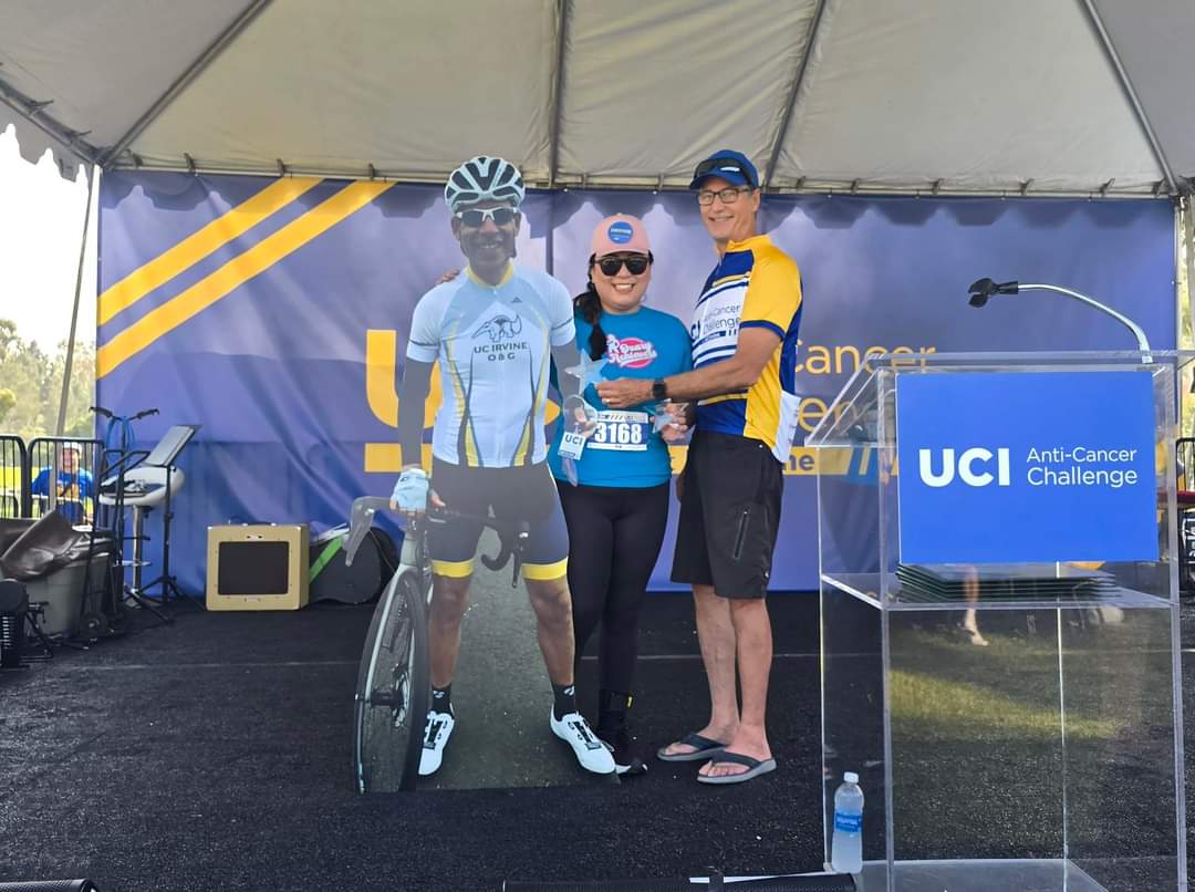 Schneider on stage holding a life-size cutout of a cyclist