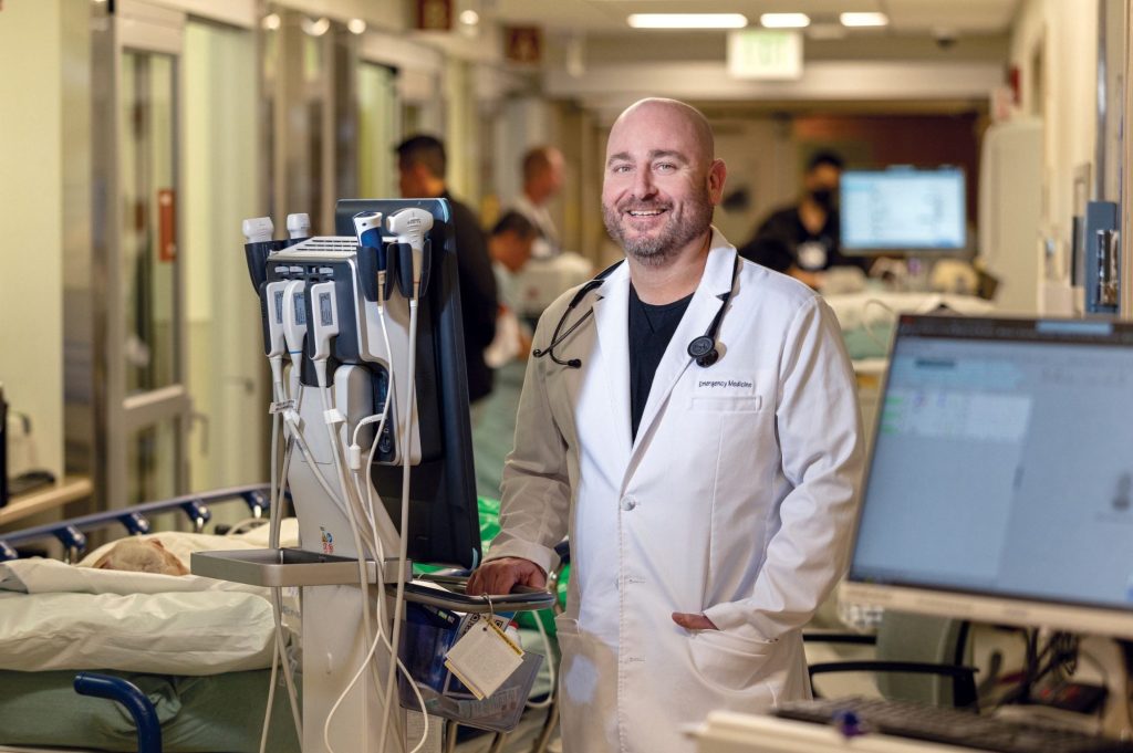 A doctor in a white coat poses on a hospital floor
