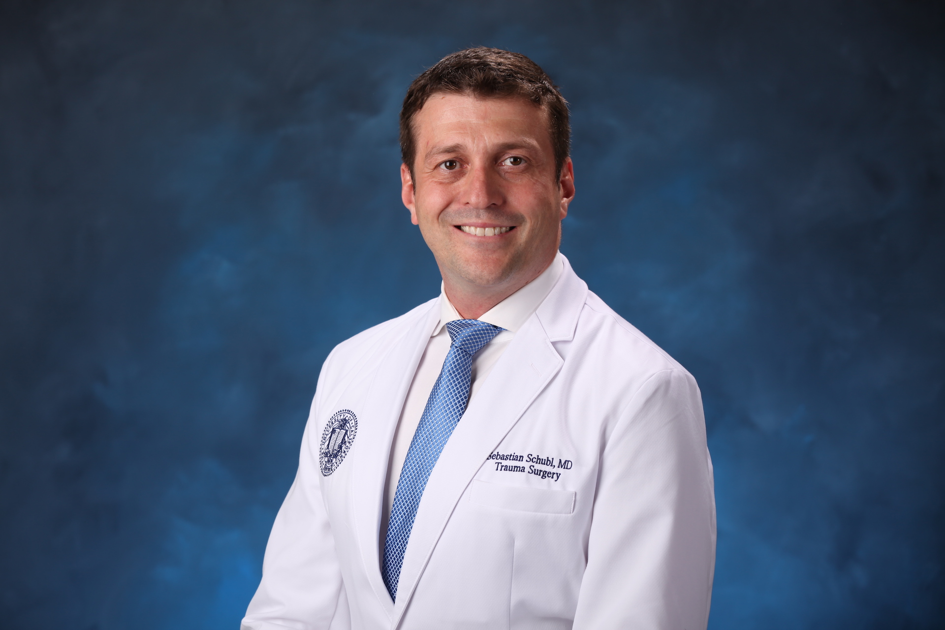 Headshot of a doctor in a white lab coat and tie