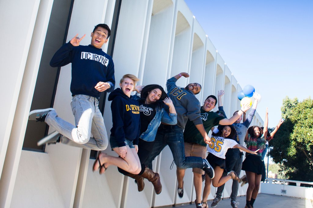 Group of UC Irvine students jumping together outside a campus building.