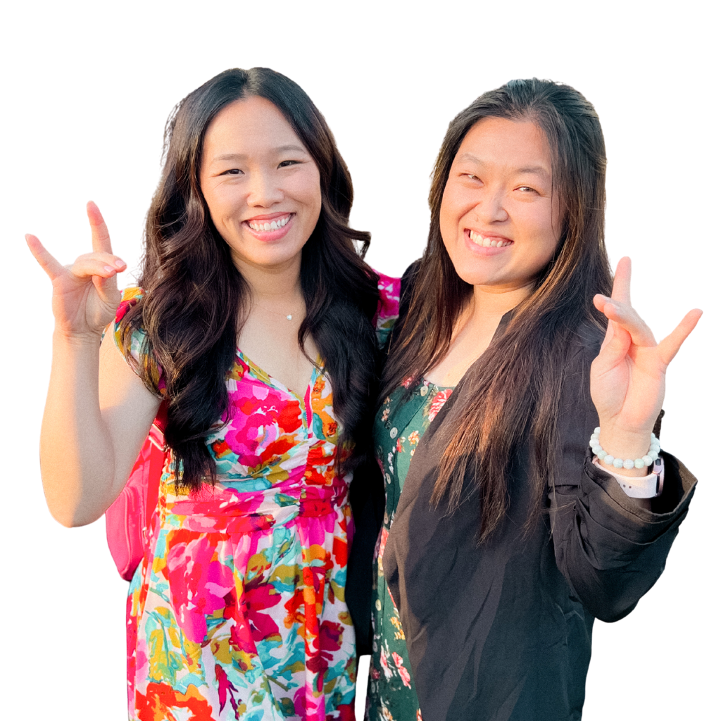 “Two people standing side by side, smiling and holding up hand gestures with pinky fingers and thumbs extended, wearing colorful floral outfits against a dark background.”