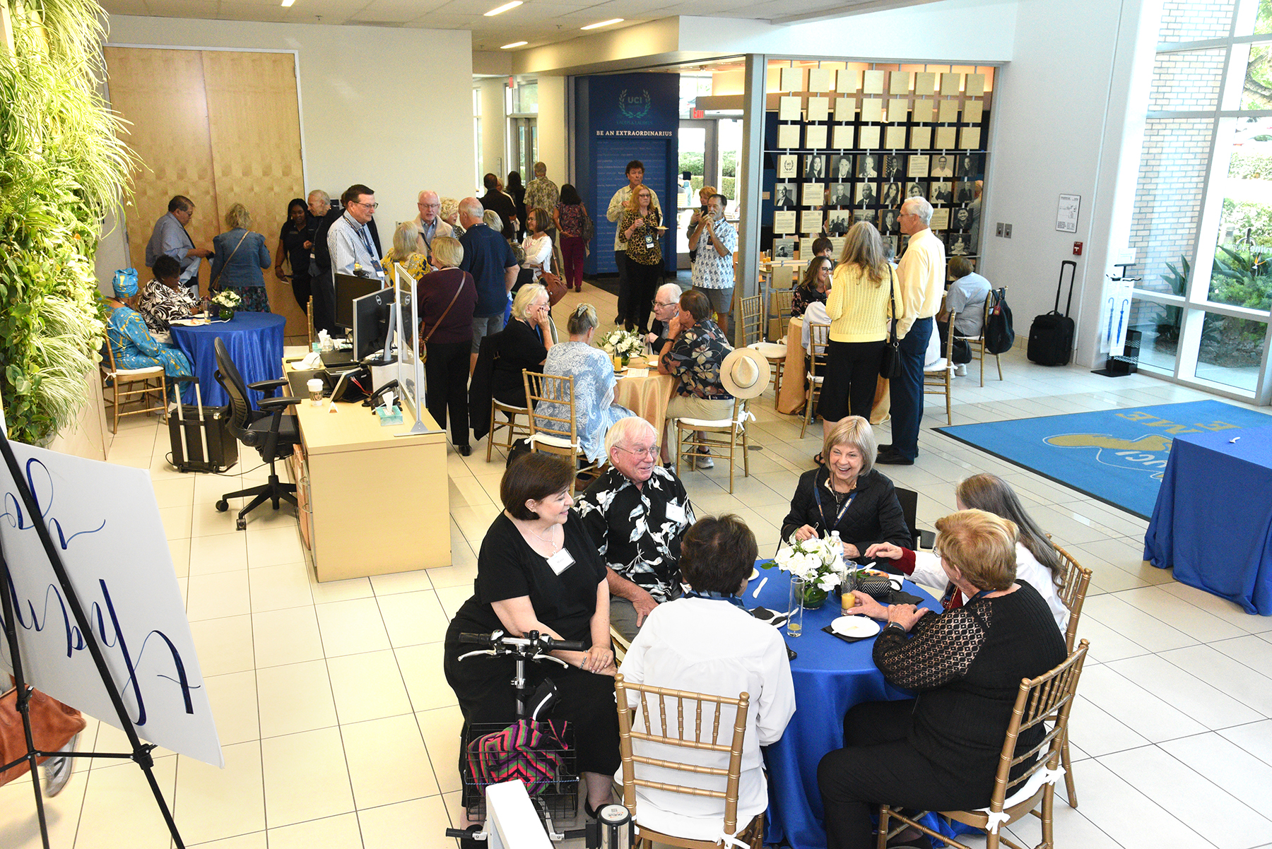 Attendees socialize at tables inside the Newman Alumni Center during a UC Irvine Alumni Golden Anteater Society celebration.